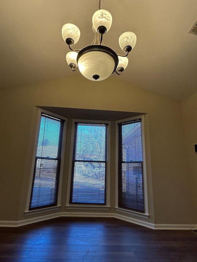 interior space featuring baseboards, vaulted ceiling, and wood finished floors