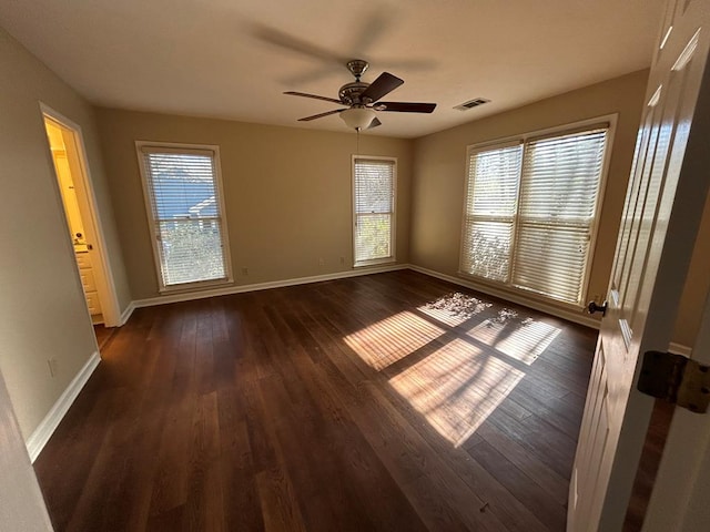 unfurnished room featuring ceiling fan, dark wood-type flooring, visible vents, and baseboards