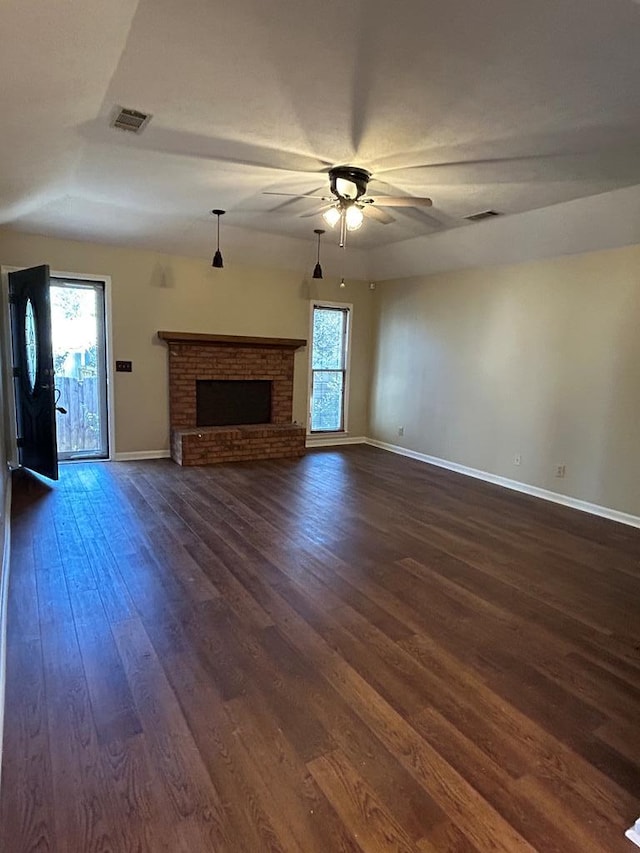 unfurnished living room featuring dark wood finished floors, visible vents, a fireplace, and ceiling fan