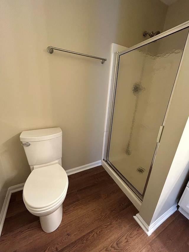 full bath featuring toilet, a shower stall, baseboards, and wood finished floors