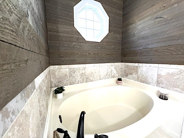 bathroom with wooden walls and a bathtub