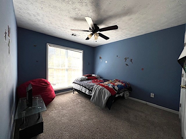 bedroom with a textured ceiling, carpet floors, and ceiling fan