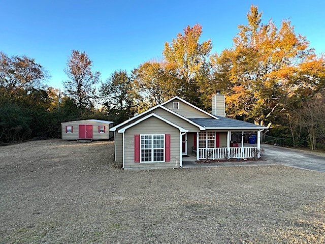 view of front facade featuring covered porch and a shed