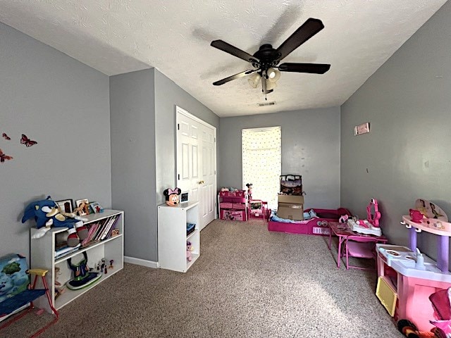 rec room with ceiling fan, carpet floors, and a textured ceiling