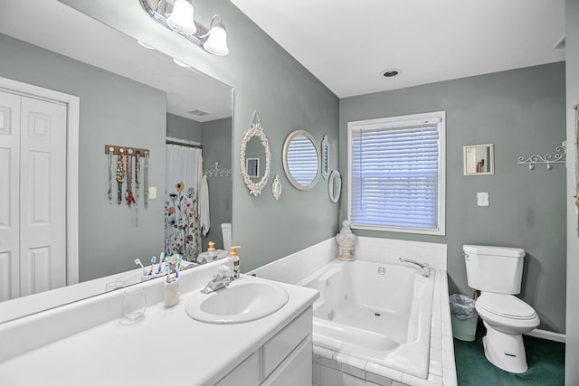 bathroom with tiled bath, vanity, and toilet