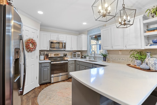 kitchen featuring kitchen peninsula, hanging light fixtures, stainless steel appliances, and sink