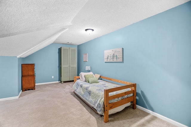 bedroom with lofted ceiling, a textured ceiling, and light carpet