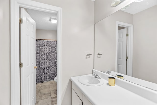 bathroom with a shower with curtain, vanity, toilet, and a textured ceiling