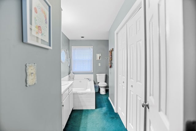 bathroom featuring vanity, a relaxing tiled tub, and toilet