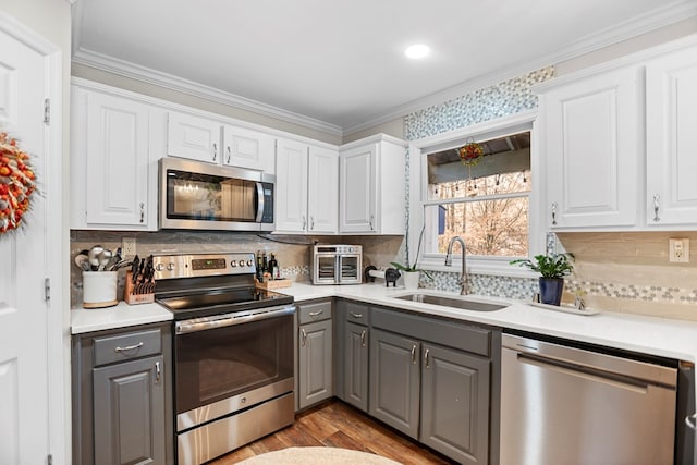 kitchen featuring white cabinets, sink, gray cabinets, ornamental molding, and appliances with stainless steel finishes