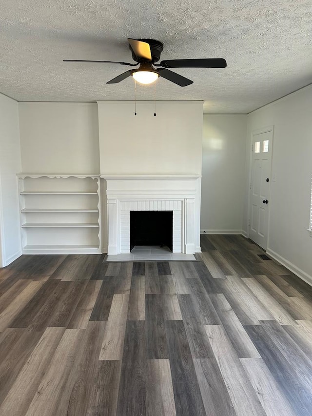 unfurnished living room with a fireplace, a textured ceiling, baseboards, and wood finished floors