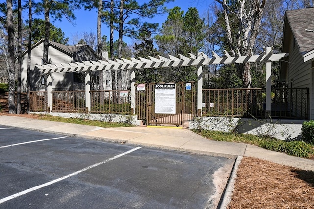 exterior space featuring a gate, fence, uncovered parking, and a pergola