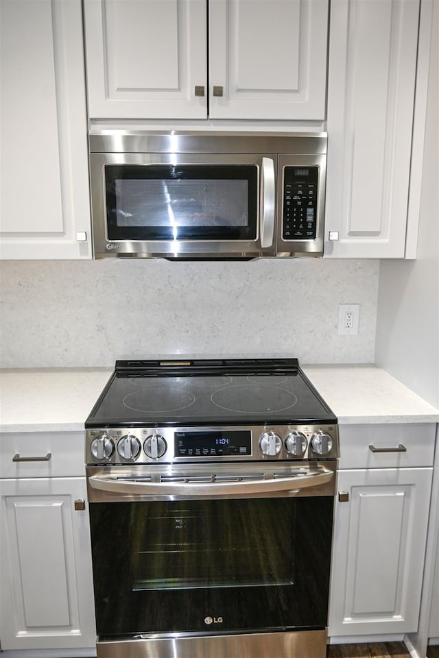 kitchen featuring stainless steel appliances, tasteful backsplash, and white cabinetry