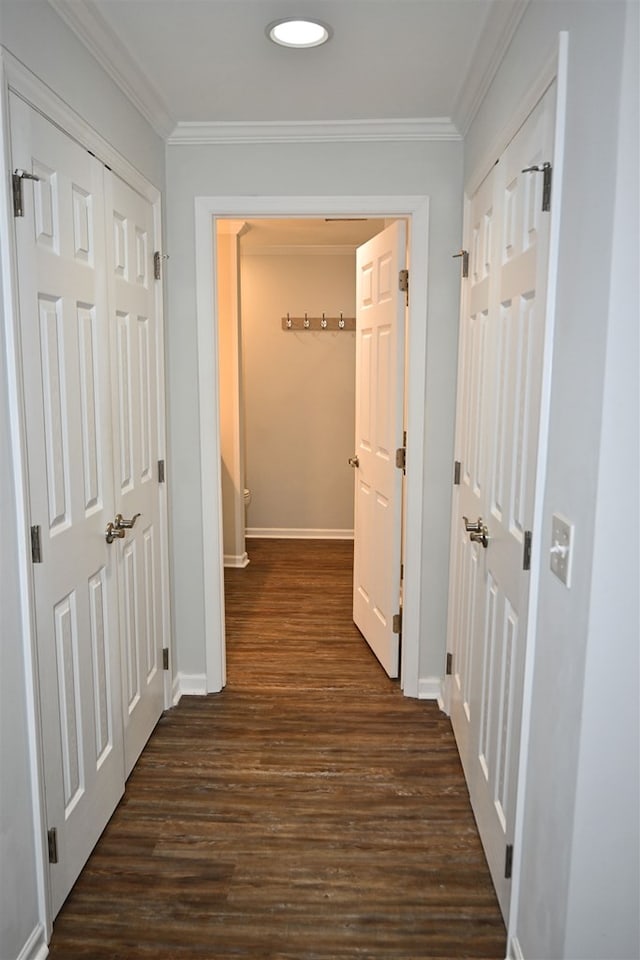 corridor with dark wood-style floors, crown molding, and baseboards