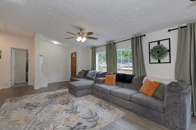 112 Huff Rd, Ellerslie, GA 31807 - living room featuring wood finished floors, a textured ceiling, a ceiling fan, and baseboards