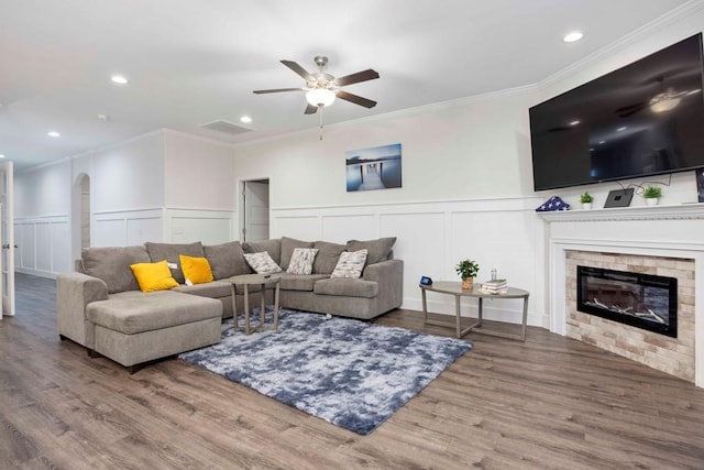 living area with ornamental molding, wainscoting, a fireplace, wood finished floors, and arched walkways