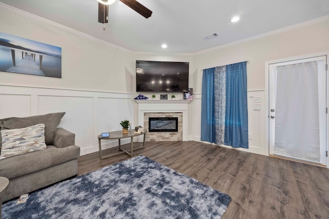 living area featuring visible vents, crown molding, a glass covered fireplace, and wood finished floors