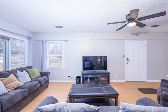 living room featuring ceiling fan, light hardwood / wood-style floors, and a textured ceiling