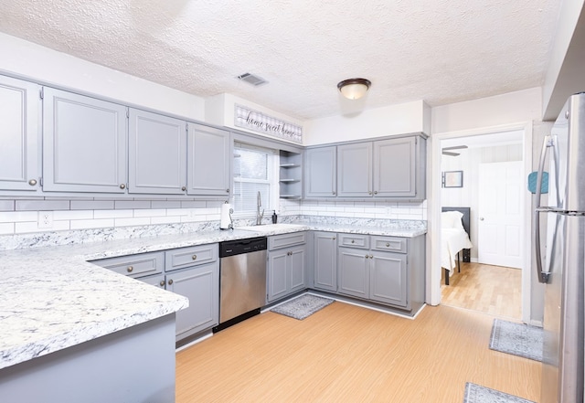 kitchen with sink, gray cabinets, appliances with stainless steel finishes, tasteful backsplash, and light hardwood / wood-style floors