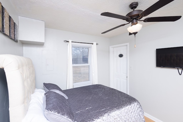 bedroom featuring ceiling fan, electric panel, and a textured ceiling