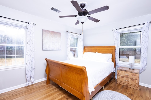 bedroom with multiple windows, ceiling fan, and light hardwood / wood-style floors