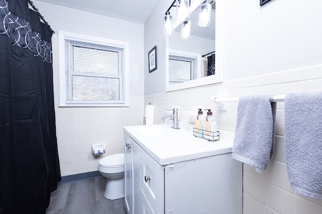 bathroom with hardwood / wood-style floors, vanity, tile walls, and toilet