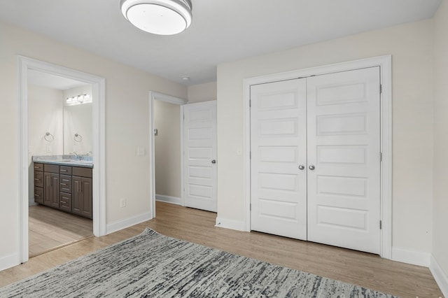 unfurnished bedroom with light wood-type flooring, ensuite bath, and a closet