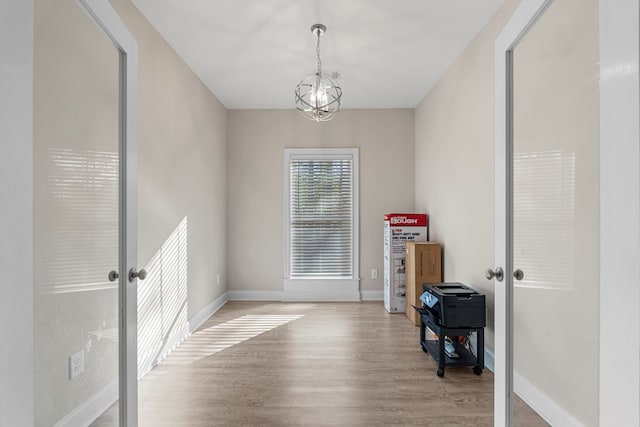 empty room with a chandelier and light wood-type flooring