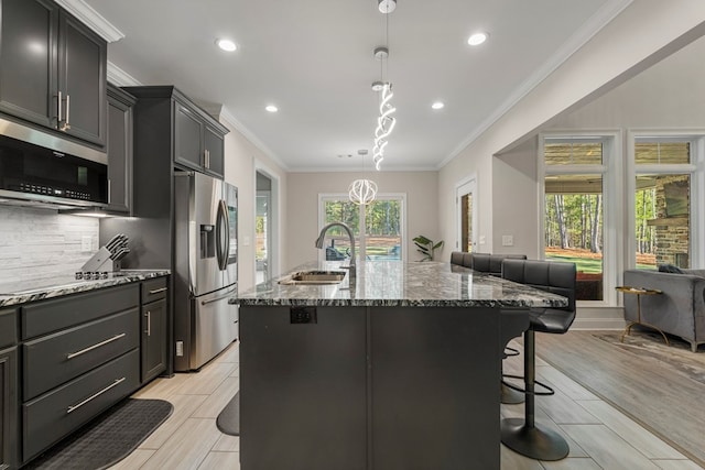 kitchen featuring a kitchen breakfast bar, sink, light wood-type flooring, an island with sink, and stainless steel appliances