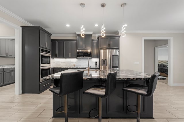 kitchen with a kitchen breakfast bar, light stone counters, stainless steel appliances, a kitchen island with sink, and pendant lighting