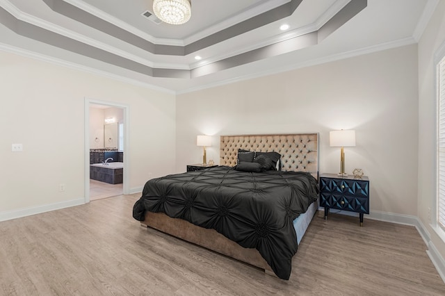 bedroom featuring hardwood / wood-style floors, connected bathroom, a tray ceiling, and ornamental molding