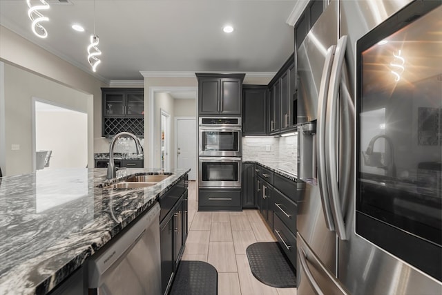 kitchen with hanging light fixtures, sink, dark stone countertops, ornamental molding, and appliances with stainless steel finishes