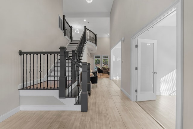 entryway with light hardwood / wood-style flooring and a towering ceiling