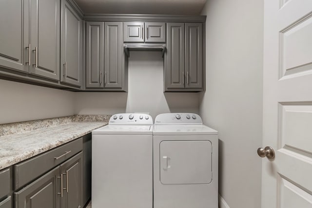 clothes washing area featuring washer and clothes dryer and cabinets