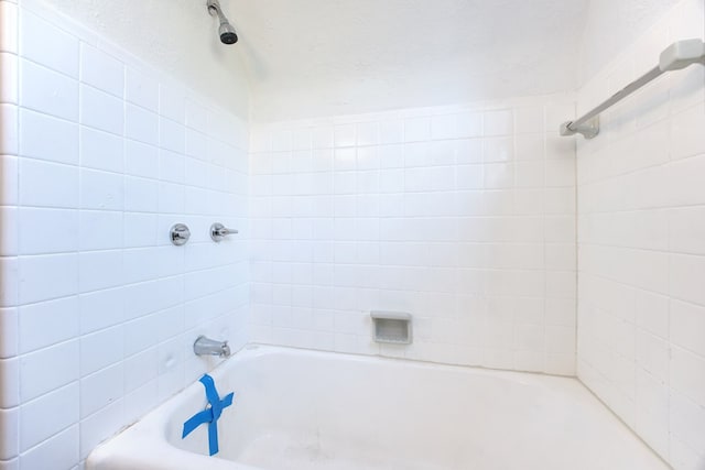 bathroom featuring tiled shower / bath combo and a textured ceiling