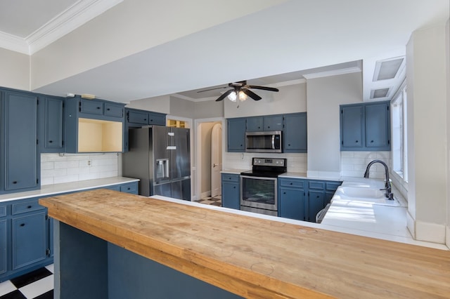 kitchen with sink, kitchen peninsula, stainless steel appliances, crown molding, and blue cabinetry