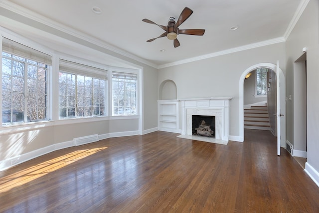 unfurnished living room featuring crown molding, a wealth of natural light, dark wood-type flooring, and a high end fireplace