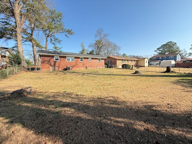 back of property featuring brick siding, a yard, and fence