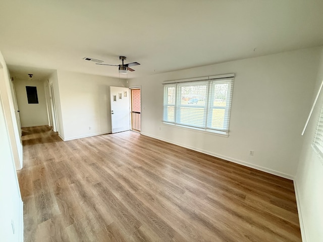 empty room with light wood-type flooring, a ceiling fan, and baseboards