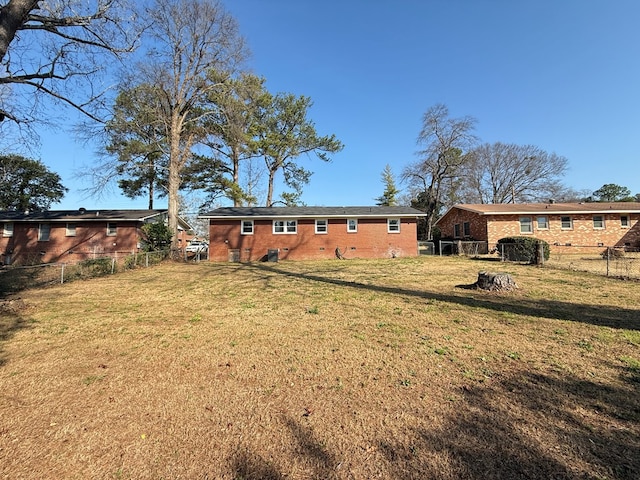 rear view of house featuring crawl space, fence private yard, brick siding, and a yard