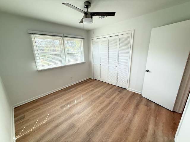 unfurnished bedroom featuring ceiling fan, a closet, wood finished floors, and baseboards