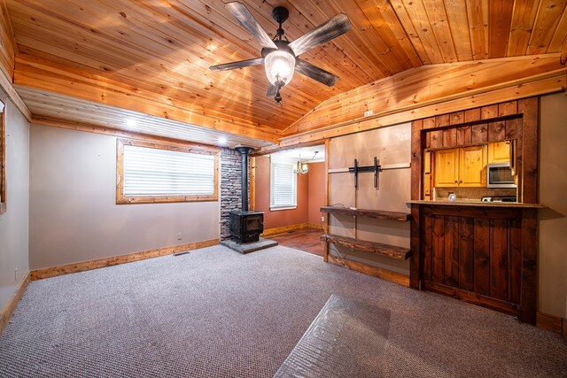 unfurnished bedroom featuring lofted ceiling, a wood stove, light carpet, and wood ceiling