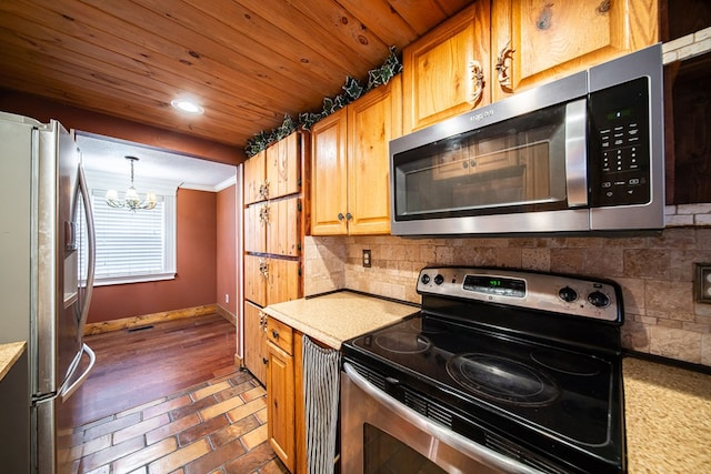 kitchen with backsplash, crown molding, pendant lighting, a chandelier, and appliances with stainless steel finishes