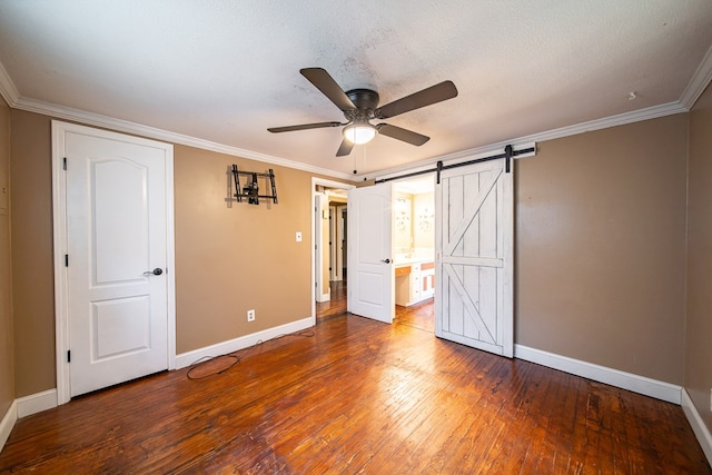 unfurnished bedroom featuring a textured ceiling, a barn door, hardwood / wood-style flooring, and ceiling fan