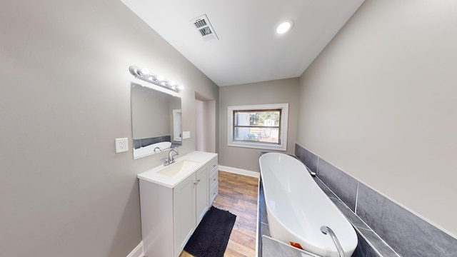 bathroom featuring hardwood / wood-style floors, vanity, and a tub