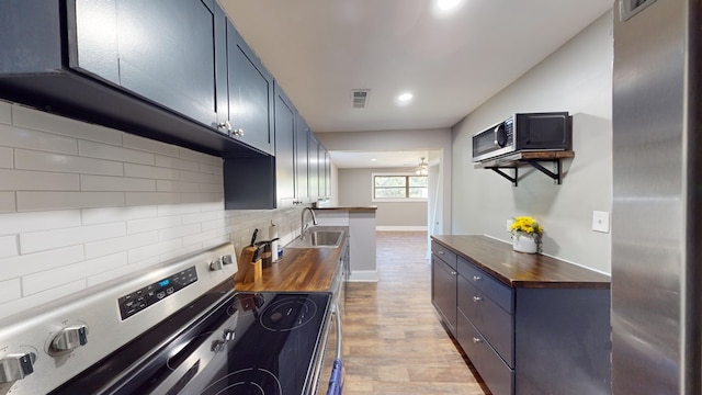 kitchen with sink, light hardwood / wood-style flooring, butcher block countertops, backsplash, and appliances with stainless steel finishes