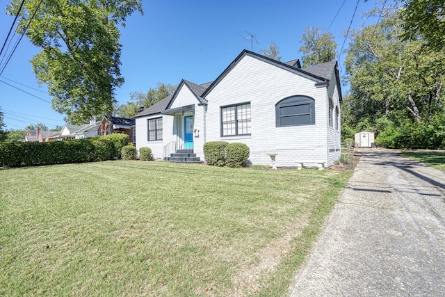 bungalow-style house with a front lawn and a storage unit