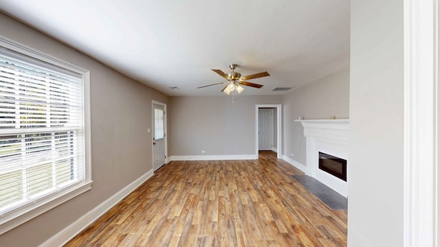 unfurnished living room featuring hardwood / wood-style floors, ceiling fan, and a wealth of natural light