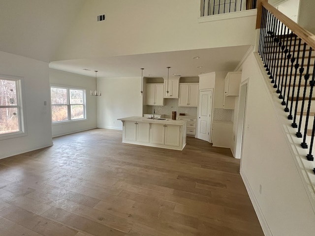 interior space with an inviting chandelier, high vaulted ceiling, sink, and light wood-type flooring