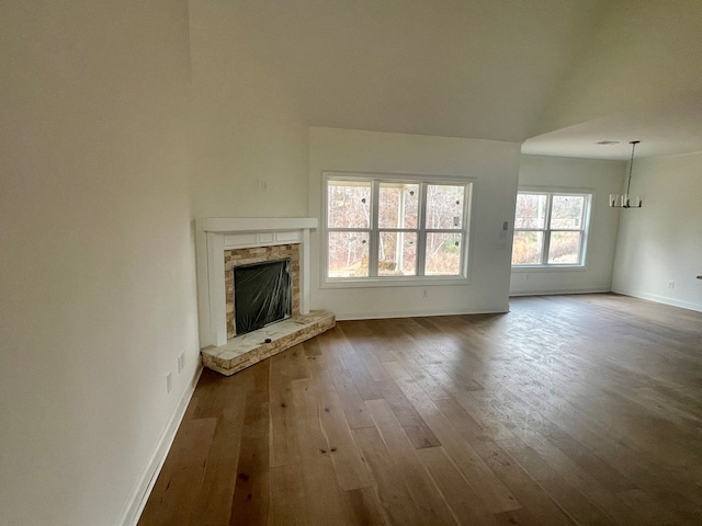 unfurnished living room with wood-type flooring and a brick fireplace